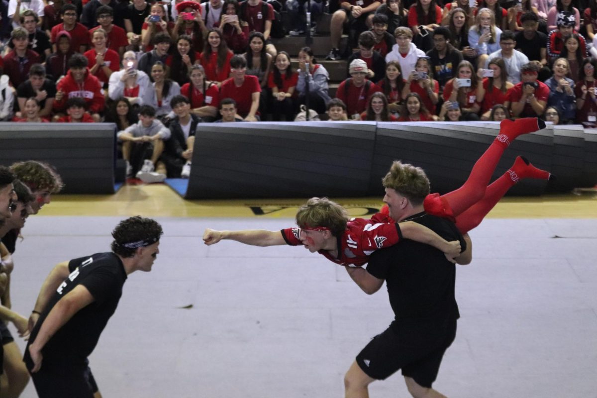 Junior Levi Goffstein bulldozes into a crowd of junior and senior boys in the Powderpuff performance at the pep rally on Friday, Sept. 22. The Powderpuff group danced and performed stunts for the junior and senior classes.