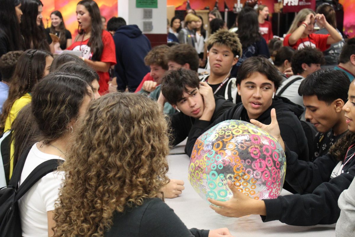 A DECA general member reads an icebreaker question that is written on a beach ball aloud. As part of this year's first DECA social, students who attended played fun games to aid them in getting to know their peers.