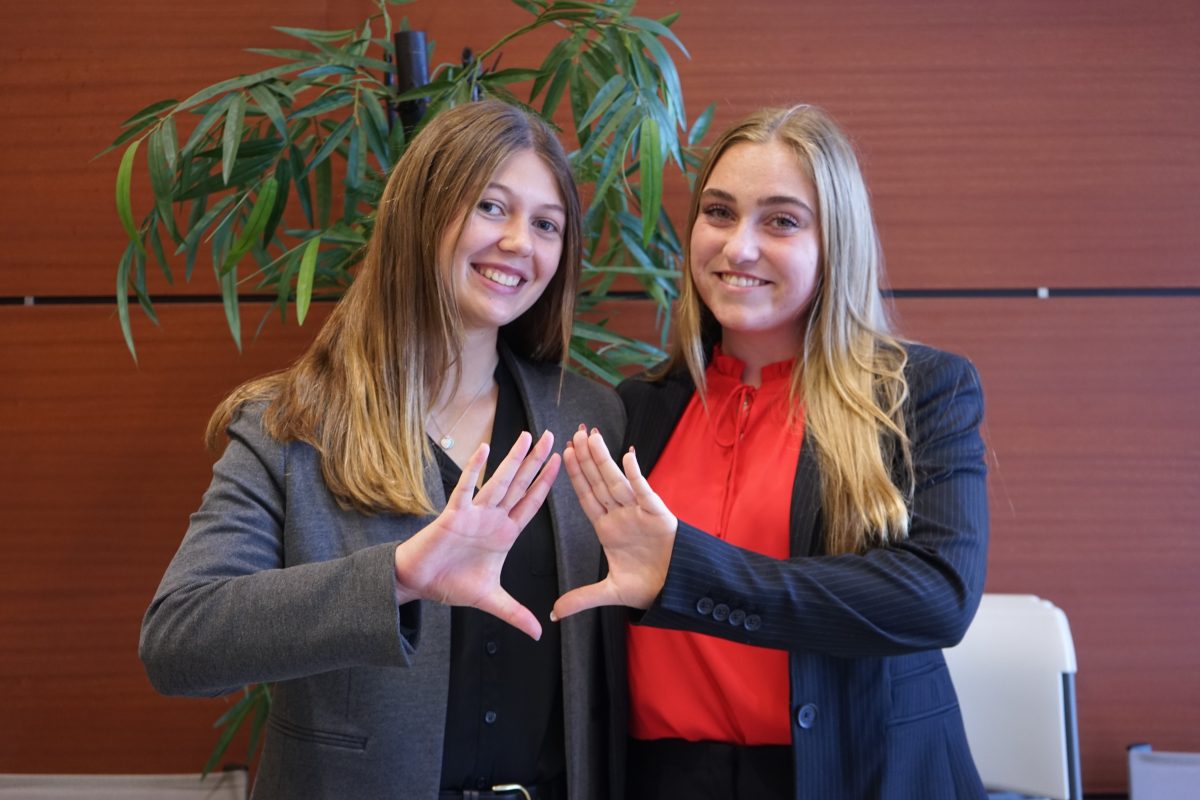 (left to right) Seniors Stephanie Bilsky and Gracyn Haynes sport the DECA symbol, a triangle, at their first career fair, hosted on Dec. 6, 2023. The career fair had 12 business for students to explore and ask questions about. "What we wanted to do is just take what we've learned [in DECA] and expand it to those students who aren't enrolled in this class and don't have access and then just kind of take it to the community and allow students to discover their future as well," Haynes said.